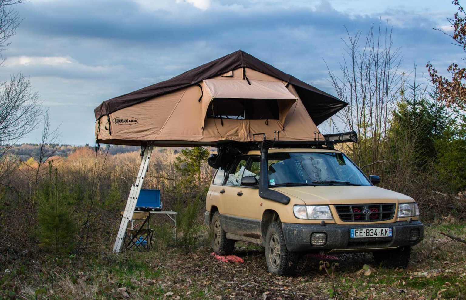 a forester with a roof tent open in the forest