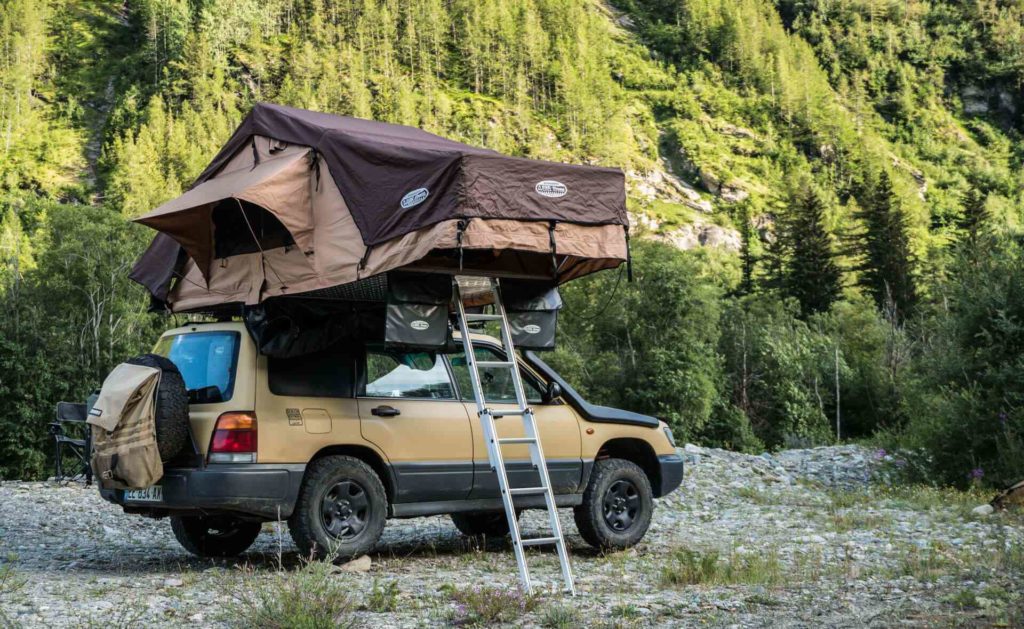 a subaru forester with a roof top tent at a camp spot in the mountains